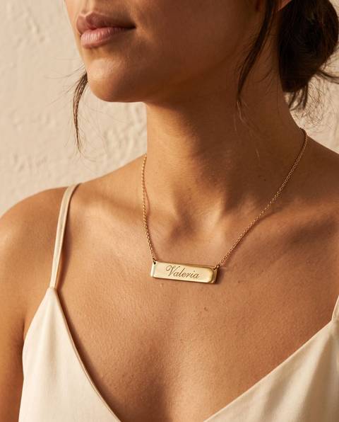 Mujer con un collar de placa dorada grabado con el nombre Valeria